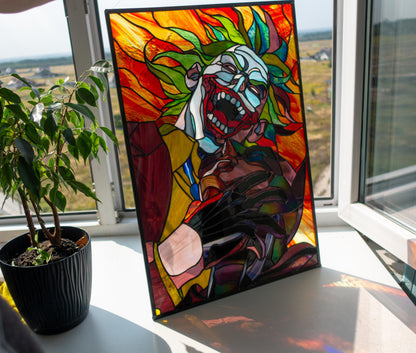 Creepy clown stained glass panel hanging in window with city view, backlit vibrant colors handmade Tiffany glass villain art