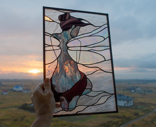 Handmade stained glass fairy girl panel held up against sunset sky, iridescent wings with burgundy dress, graceful feminine figure, Tiffany copper foil technique