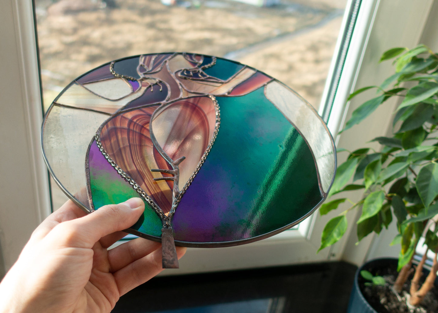 Round stained glass feminine figure close-up — black patina finish, soft pink iridescent tones, handcrafted in Kyiv