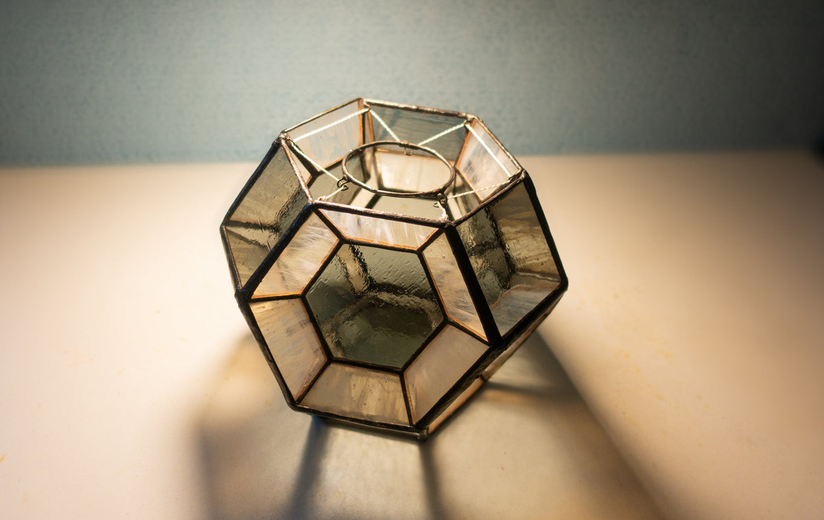 Handmade geometric hexagon stained glass lamp on table in warm light, clear and amber glass panels with copper foil, Art Deco style candle holder or night light