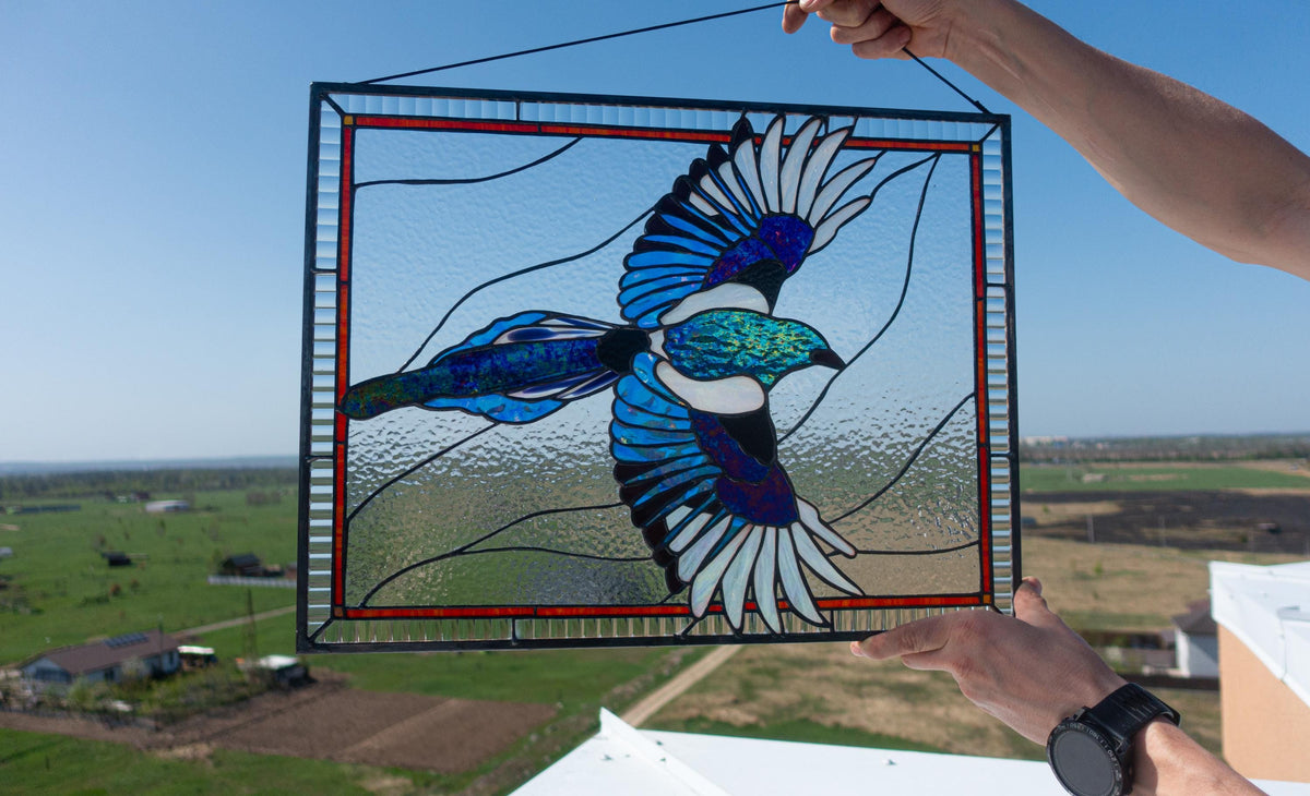 Comparison of old black vs new black iridescent glass in magpie stained glass panel — shows color shift effect of specialty iridescent glass