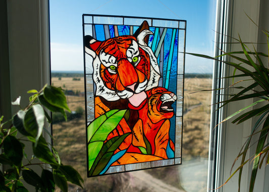 Stained glass panel of a tiger in front of a window with a view of a field.